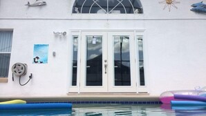 Un bâtiment doté d’une piscine, d’une grande fenêtre en arc de cercle et d’une porte à panneaux de verre.