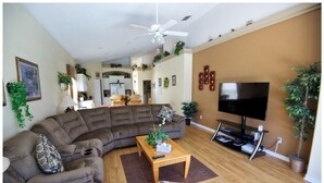 A living room with a sectional sofa, a coffee table, a flat-screen TV, and a ceiling fan. - Ov1584 - Glenbrook Resort - 4 Bed 3 Baths Villa (Clermont)