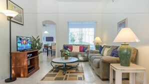Una sala de estar con televisor, sofá, mesa de centro y lámparas.
