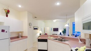 Una cocina moderna con gabinetes blancos, lavavajillas, estufa y pileta.