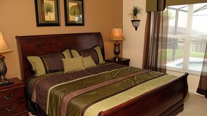 A bedroom with a large bed, two bedside tables, a nightstand, a window with blinds, and two wall-mounted lamps. - Ov2564 - Windsor Palms Resort - 4 Bed 2 Baths Townhome (Kissimmee)