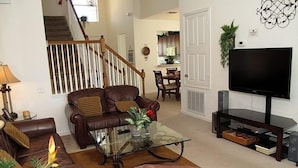 A living room with a brown leather sofa, a glass coffee table, and a television on a stand. - Ov2484 - Windsor Hills Resort - 5 Bed 5 Baths Villa (Kissimmee)