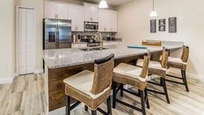 A kitchen with white cabinets, stainless steel appliances, a granite countertop, and wicker chairs. - Ov2069 - Paradise Palms - 2 Bed 1 Baths Villa (Kissimmee)