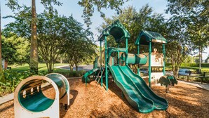 A playground with a slide, climbing structures, and a tunnel.