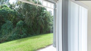 A covered outdoor area with a grassy lawn and dense foliage in the background.