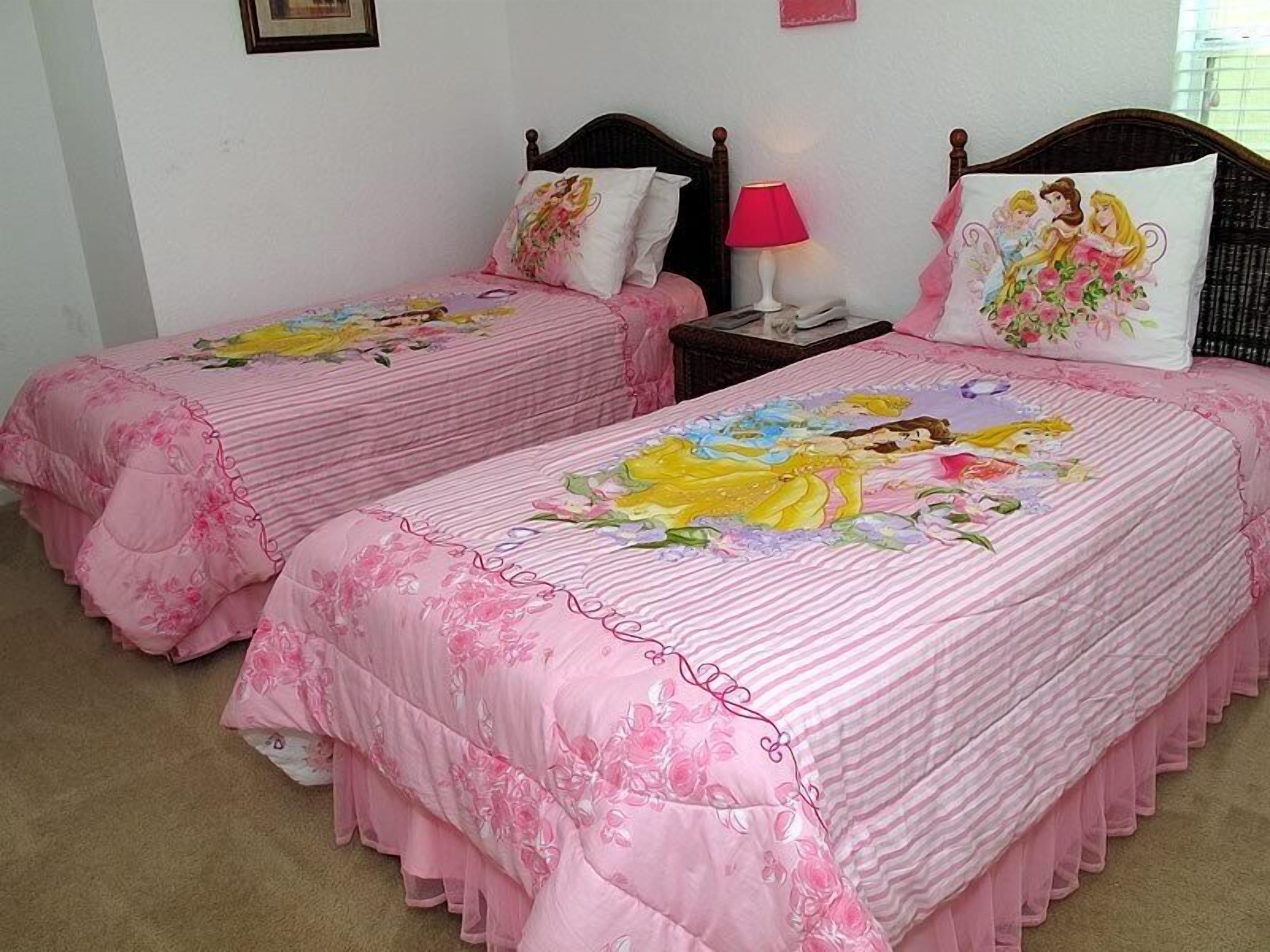 A bedroom with two beds, each with floral bedding and a pink color scheme.