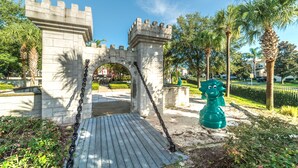 A stone archway with a wooden deck leading through it, surrounded by palm trees and greenery. - Ov2605 - Windsor Hills Resort - 5 Bed 5 Baths Villa (Kissimmee)