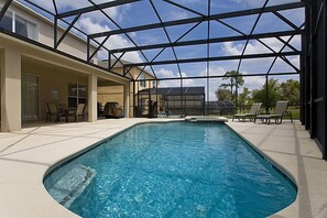 A swimming pool with a glass ceiling, surrounded by lounge chairs and a covered patio area.