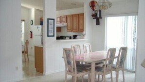 A dining area with a round table and six chairs, a kitchen with wooden cabinets, and a chandelier. - Ov1761 - Davenport Lakes - 4 Bed 2 Baths Villa (Davenport)