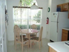 A small kitchen with a round table and four chairs, a white refrigerator, and a window with a white curtain. - Ov1761 - Davenport Lakes - 4 Bed 2 Baths Villa (Davenport)