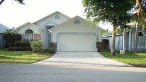 A single-story house with a central garage door, a small front porch, and a driveway leading to the garage. - Ov1761 - Davenport Lakes - 4 Bed 2 Baths Villa (Davenport)
