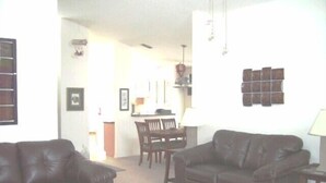 A living room with two leather sofas, a dining table with chairs, and a kitchen area in the background. - Ov1761 - Davenport Lakes - 4 Bed 2 Baths Villa (Davenport)