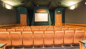 A movie theater with rows of orange seats, a large screen, and a projector. - Ov2545 - Windsor Hills Resort - 5 Bed 5 Baths Villa (Kissimmee)