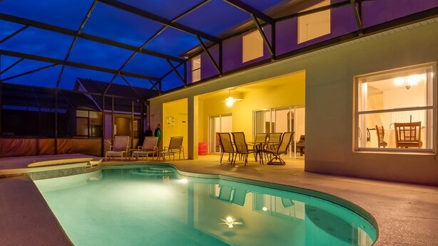 Une piscine intérieure dotée d’un toit en verre, entourée de chaises longues et d’un espace salon.