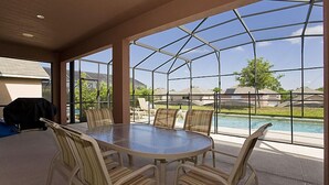 An indoor patio with a glass enclosure, a round table, and chairs. - Ov1969 - Emerald Island - 6 Bed 5 Baths Villa (Kissimmee)