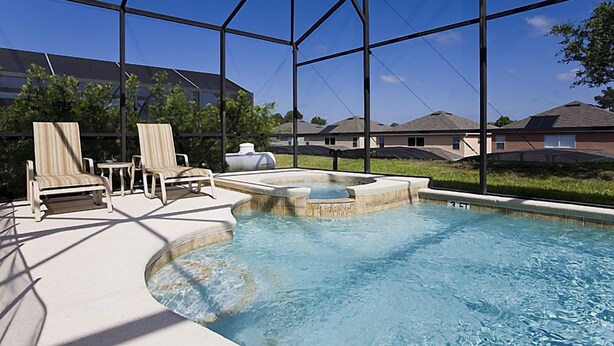 A swimming pool with lounge chairs and a hot tub, surrounded by a covered area with a view of houses. - Ov1969 - Emerald Island - 6 Bed 5 Baths Villa (Kissimmee)