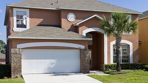 A single-story house with a white garage door, a small attached garage, and a front yard with a palm tree. - Ov1969 - Emerald Island - 6 Bed 5 Baths Villa (Kissimmee)