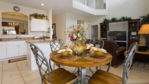 A modern kitchen with white cabinets, a dining area with a wooden table and chairs, and a small balcony with a railing. - Ov1969 - Emerald Island - 6 Bed 5 Baths Villa (Kissimmee)