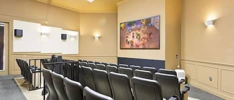 A conference room with rows of chairs, a projector screen, and a large painting on the wall.