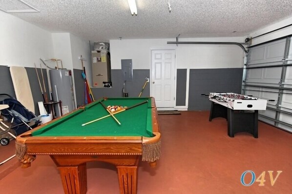 A room with a pool table, a foosball table, and a door.