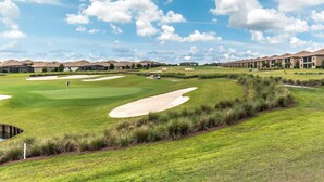 En golfbana med bunkrar, en puttinggreen och ett klubbhus i bakgrunden.
