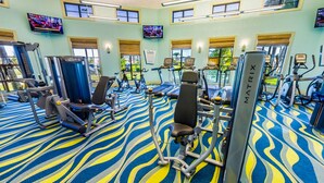 Ett gym med olika typer av träningsutrustning, inklusive löpband, motionscyklar och styrketräningsmaskiner.