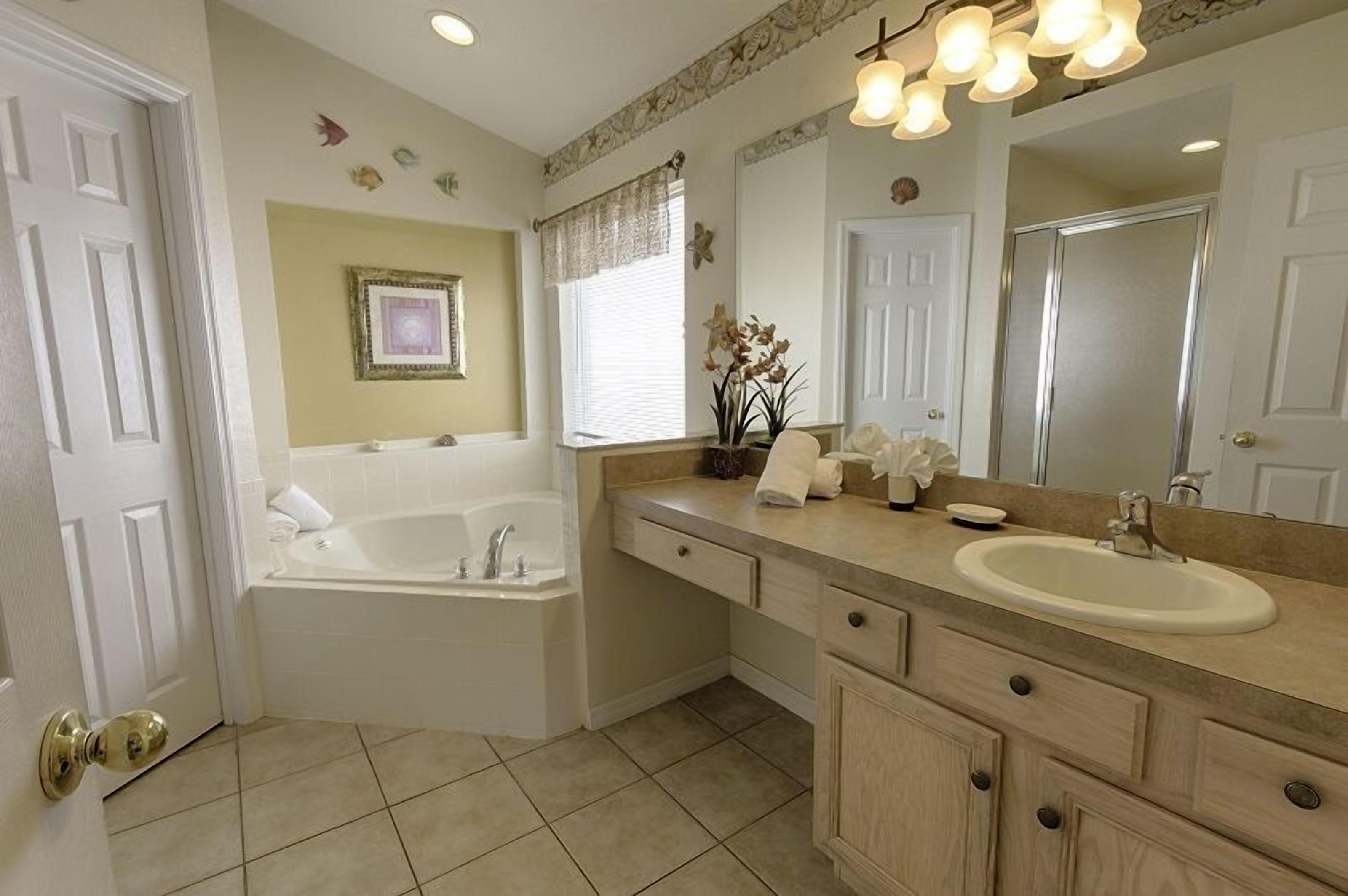 A bathroom with a bathtub, vanity, sink, and large mirror.