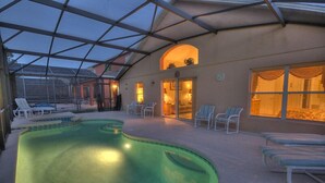 An indoor swimming pool with lounge chairs and a covered patio area.