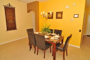 A dining area with a wooden table and chairs, yellow walls, and a chandelier. - Ov1953 - Windsor Palms Resort - 4 Bed 3 Baths Townhome (Kissimmee)