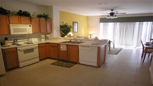 A kitchen with wooden cabinets, a microwave, stove, and dishwasher. There is a dining area with a table and chairs.