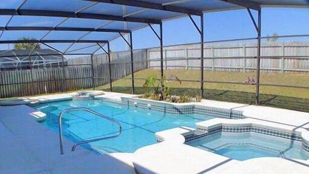 A covered outdoor swimming pool with multiple sections, including a hot tub area, surrounded by a fenced yard. - Ov2186 - Lindfields - 5 Bed 3 Baths Villa (Kissimmee)