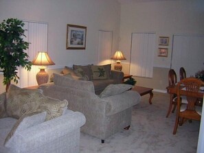 A living room with two sofas, a coffee table, and a dining area with chairs. There are two lamps on the side tables. - Ov2186 - Lindfields - 5 Bed 3 Baths Villa (Kissimmee)