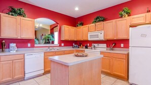 A modern kitchen with wooden cabinets, a central island, a microwave, and a refrigerator.