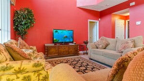 A living room with a red wall, a television, a sofa, and a patterned rug.