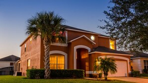 A two-story house with a garage, a well-maintained lawn, and a palm tree.