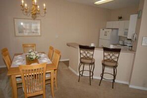 A dining area with a wooden table set for six, surrounded by six chairs. A chandelier hangs above the table. - Ov1484 - Emerald Island - 4 Bed 3.5 Baths Townhome (Kissimmee)