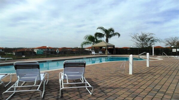 A swimming pool with lounge chairs and a covered seating area.