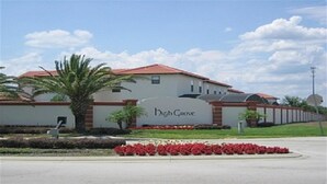 A building with a sign reading "High Grove" and a palm tree in the foreground. - Ov2749 - High Grove - 4 Bed 3 Baths Villa (Clermont)