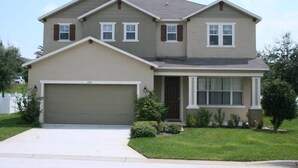 A two-story house with a garage, a front porch, and a well-maintained lawn.