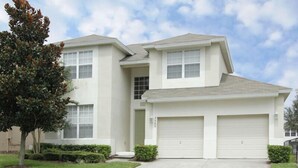 A two-story house with a garage, a driveway, and a tree.
