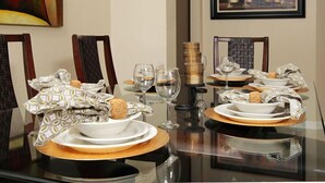 A dining table set for four with white plates, gold chargers, and clear wine glasses.