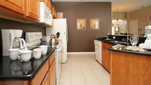 A modern kitchen with wooden cabinets, a white refrigerator, a coffee maker, and a dishwasher.