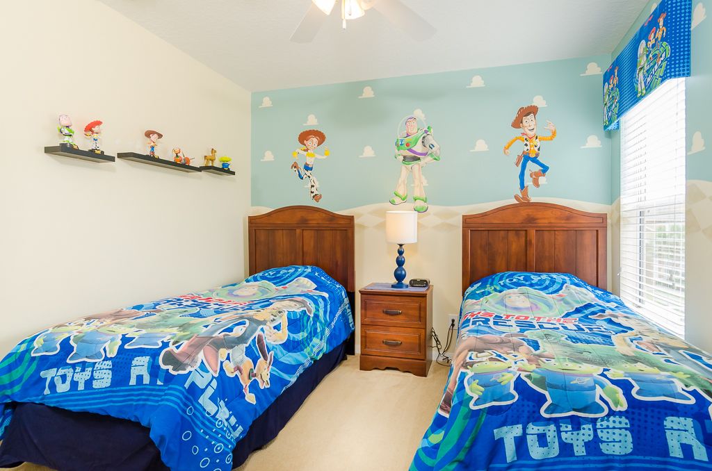 Een slaapkamer met twee bedden, houten hoofdborden, een nachtkastje, een lamp en een muur met een blauw-wit muurschildering.