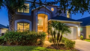 A two-story house with a large garage, a covered front porch, and a well-maintained lawn. - Ov535 - Emerald Island - 7 Bed 4 Baths Villa (Kissimmee)