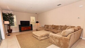 A living room with a beige sectional sofa, a flat-screen TV, and a potted plant. - Ov2630 - Bella Vida Resort - 6 Bed 5.5 Baths Villa (Kissimmee)