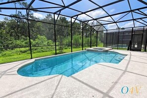 A swimming pool with a curved edge, surrounded by a covered area with a metal frame and glass panels.
