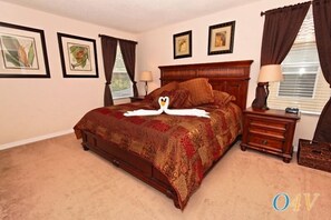 A bedroom with a large bed, two bedside tables, and framed pictures on the walls.