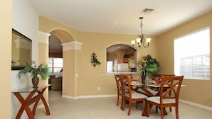 A dining area with a table and chairs, a chandelier, and a window with blinds. - Ov2116 - Windsor Hills Resort - 6 Bed 4 Baths Villa (Kissimmee)
