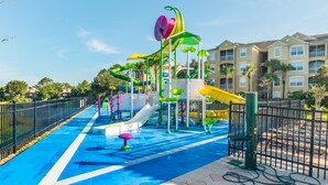 A water park with slides and play structures, surrounded by a fence and buildings in the background. - Ov1848 - Windsor Hills Resort - 6 Bed 4 Baths Villa (Kissimmee)