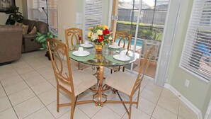 A dining area with a glass table, wooden chairs, and a flower vase. - Ov1848 - Windsor Hills Resort - 6 Bed 4 Baths Villa (Kissimmee)